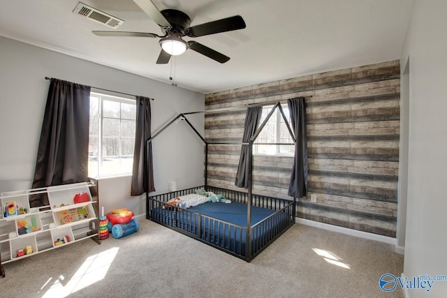 bedroom with visible vents, multiple windows, wood walls, and carpet