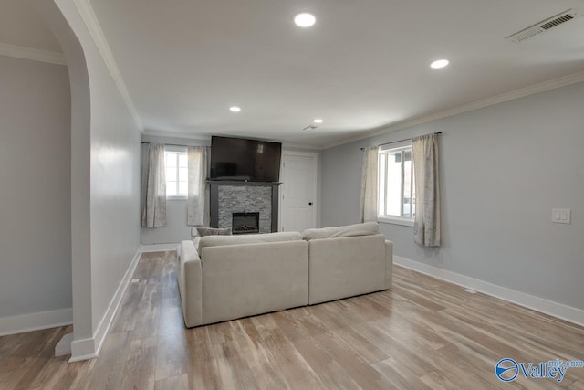 unfurnished living room with a stone fireplace, crown molding, visible vents, and light wood-type flooring