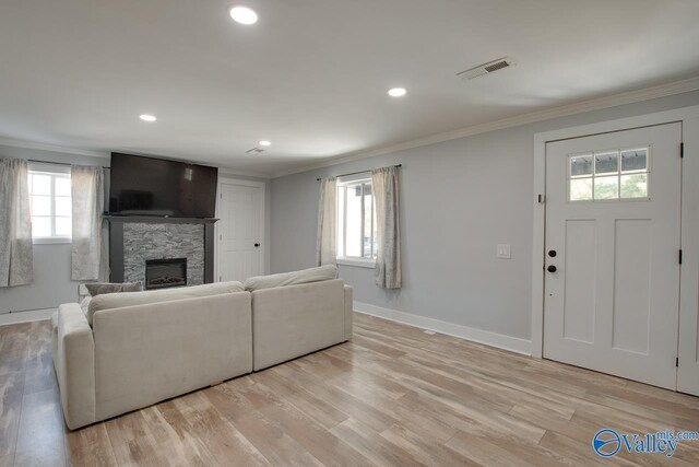 living room with visible vents, baseboards, ornamental molding, a fireplace, and light wood-style floors