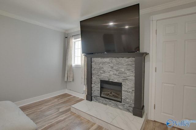 living area featuring a glass covered fireplace, wood finished floors, and ornamental molding