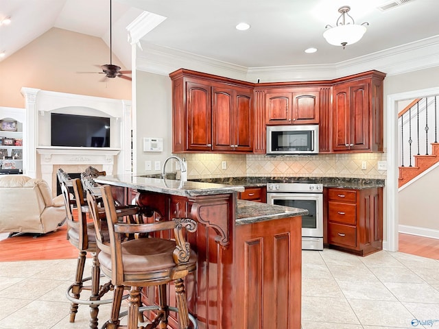 1103 Blackbriar Cir, Hartselle, AL 35640 - kitchen featuring stainless steel appliances, light tile patterned flooring, a peninsula, a kitchen bar, and a ceiling fan