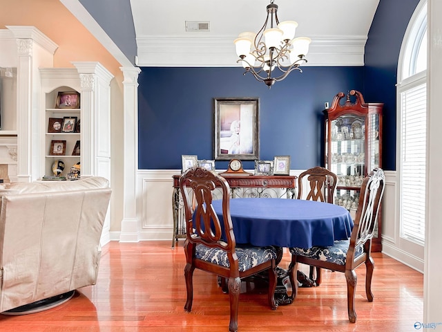 1103 Blackbriar Cir, Hartselle, AL 35640 - dining space featuring a chandelier, wainscoting, decorative columns, a decorative wall, and wood finished floors