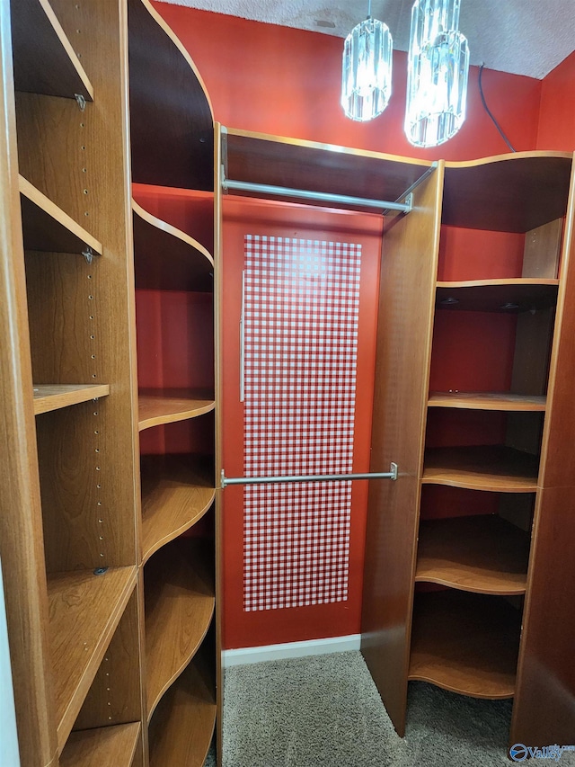 walk in closet with carpet floors and a chandelier