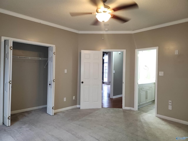 unfurnished bedroom with ensuite bathroom, baseboards, a closet, crown molding, and carpet floors