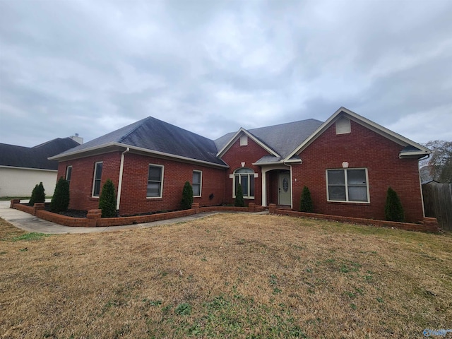 ranch-style home with a front lawn, brick siding, and a shingled roof