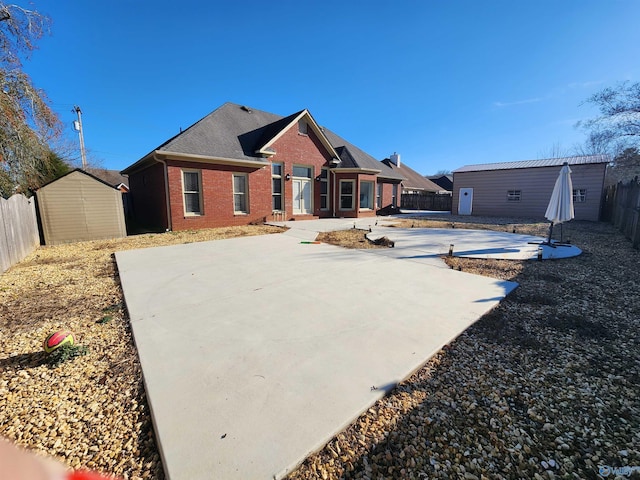 back of property with a fenced backyard, a storage shed, an outdoor structure, a patio, and brick siding