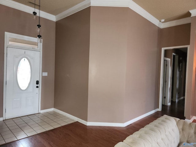 entryway featuring wood finished floors, visible vents, baseboards, and ornamental molding