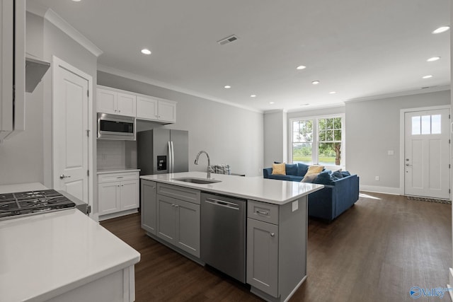 kitchen with dark wood-type flooring, sink, an island with sink, appliances with stainless steel finishes, and ornamental molding