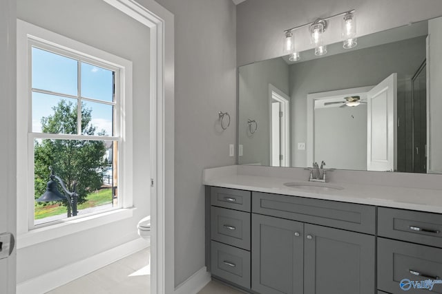 bathroom with a wealth of natural light, ceiling fan, vanity, and toilet