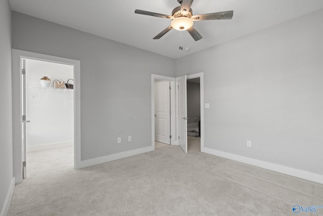 unfurnished bedroom featuring ceiling fan, a closet, light carpet, and a spacious closet