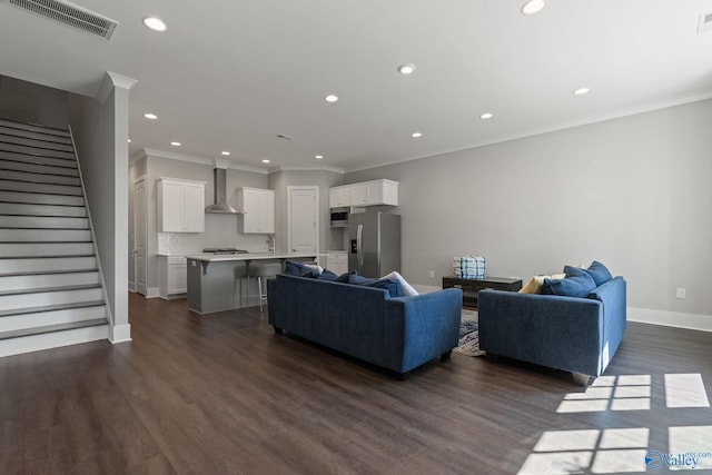 living room with sink, crown molding, and dark hardwood / wood-style flooring