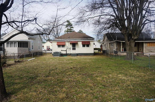 rear view of property with central air condition unit, fence, and a lawn