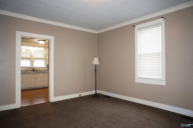 unfurnished room featuring baseboards, visible vents, dark colored carpet, crown molding, and a sink