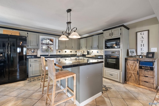 kitchen with black appliances, gray cabinetry, a breakfast bar area, and a kitchen island