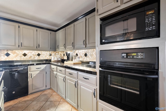 kitchen featuring light tile patterned floors, tile counters, decorative backsplash, crown molding, and black appliances