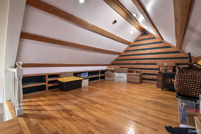 bonus room featuring a wood stove, hardwood / wood-style floors, and lofted ceiling with beams