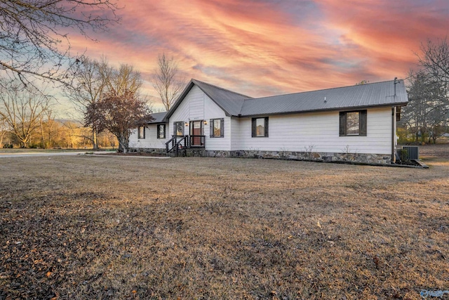 view of front of house with a yard and central AC