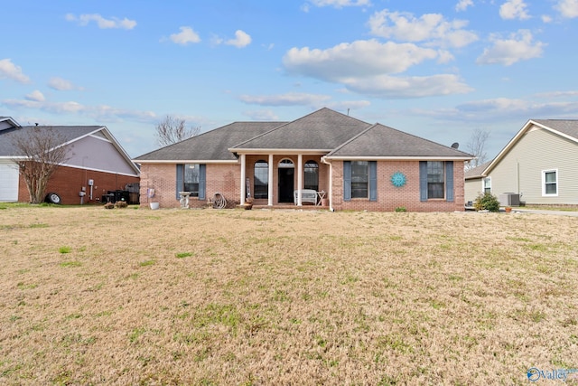 view of front of house with brick siding, a shingled roof, central AC unit, and a front lawn