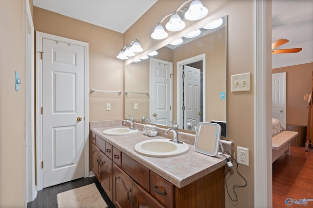 ensuite bathroom featuring ensuite bathroom, double vanity, a sink, and wood finished floors