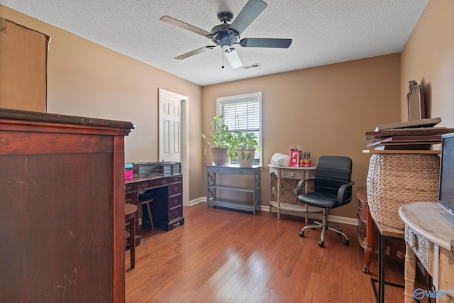 home office with a textured ceiling, ceiling fan, baseboards, and hardwood / wood-style flooring