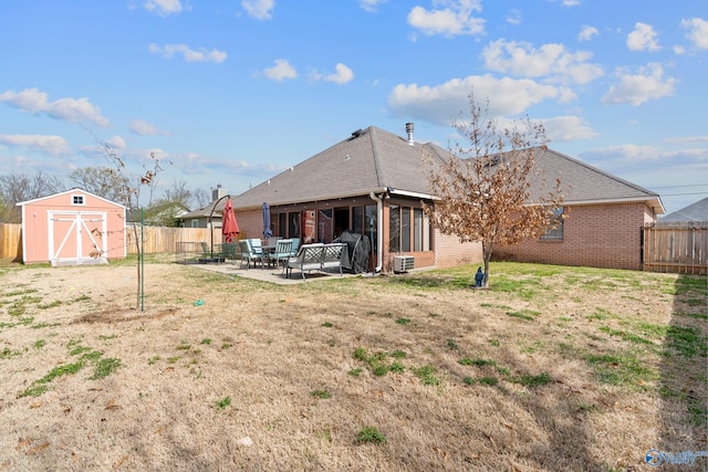 back of property with an outdoor structure, a patio, a fenced backyard, brick siding, and a storage shed
