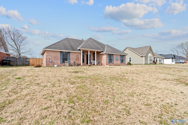 view of front facade with brick siding, fence, and a front lawn