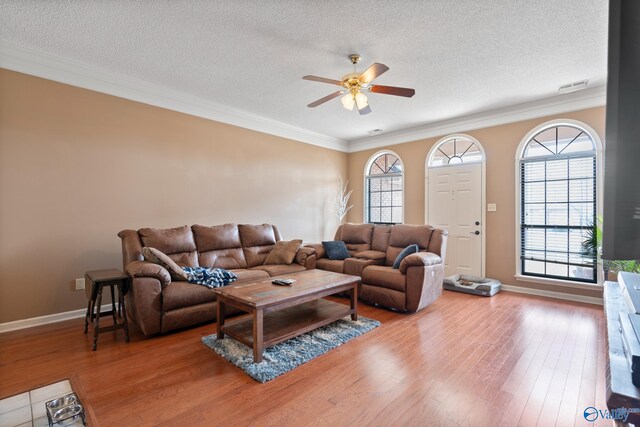 living room featuring a textured ceiling, ceiling fan, wood finished floors, and crown molding