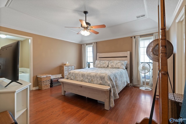 bedroom featuring ornamental molding, a textured ceiling, visible vents, ceiling fan, and wood finished floors