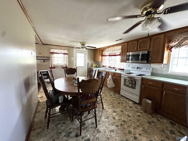 kitchen featuring electric range, ceiling fan, stone finish floor, plenty of natural light, and stainless steel microwave
