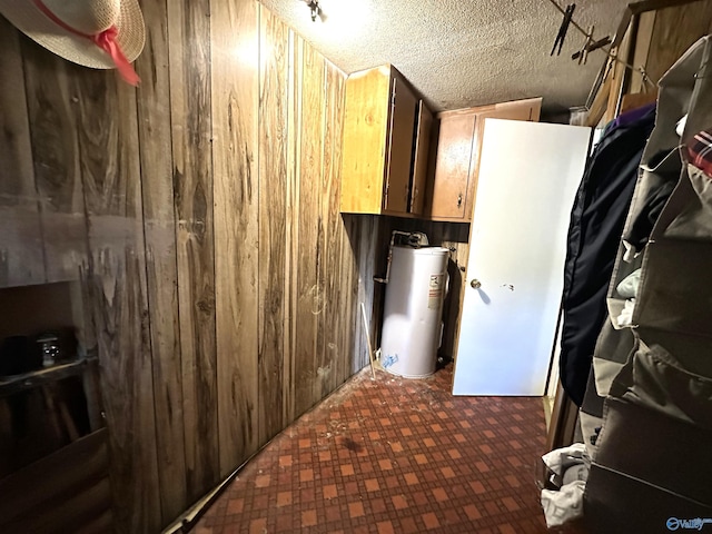 interior space featuring gas water heater, wood walls, and a textured ceiling