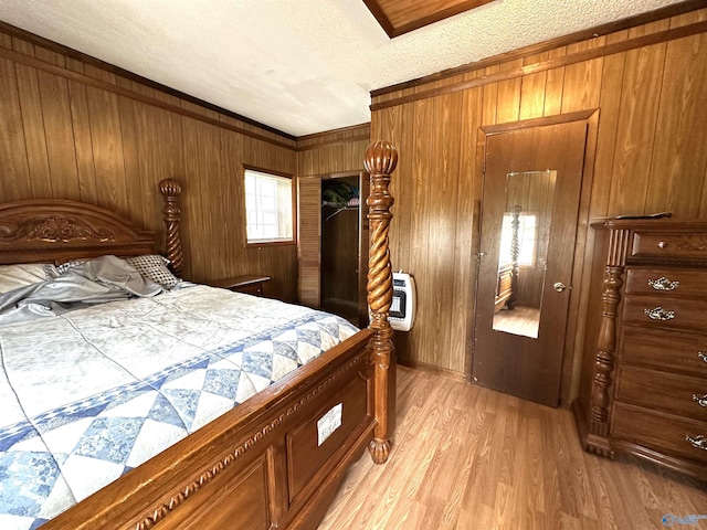 bedroom with wooden walls, a textured ceiling, heating unit, and light wood-style flooring