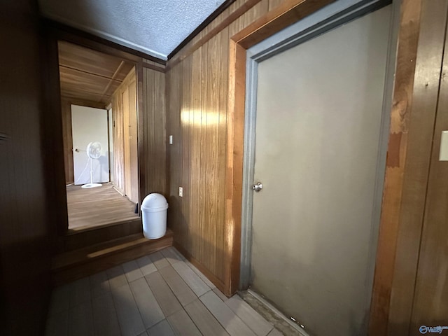 hall featuring a textured ceiling and wood walls