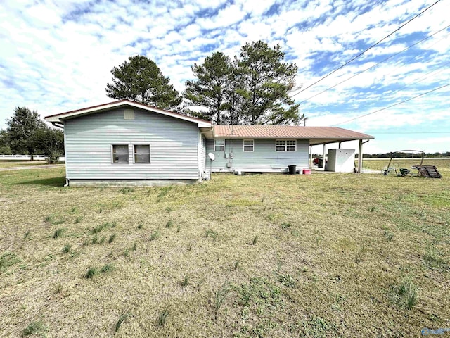 back of property featuring a yard and metal roof