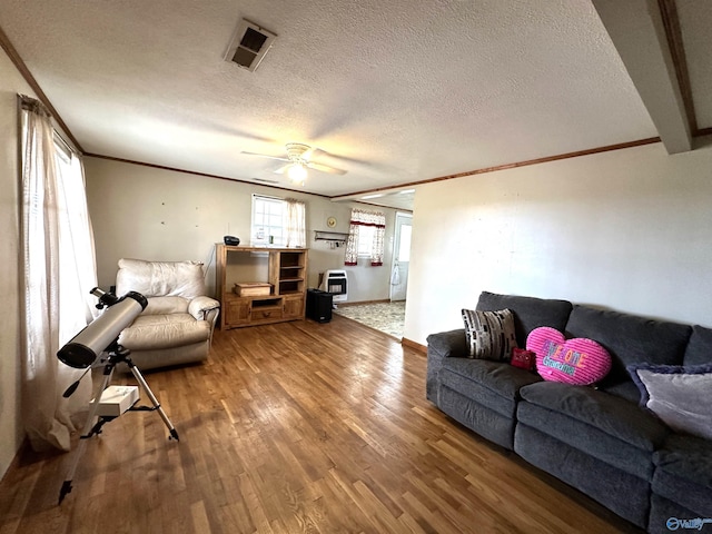 living room featuring wood-type flooring, crown molding, a textured ceiling, and ceiling fan