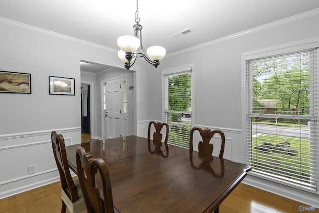 dining area featuring a wainscoted wall, ornamental molding, visible vents, and a notable chandelier