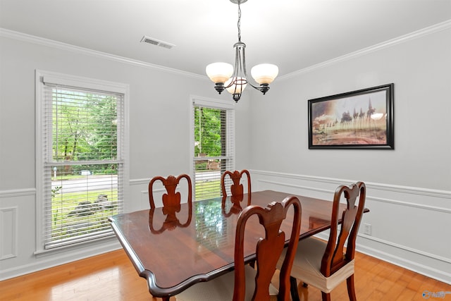 dining room featuring visible vents, light wood-style floors, ornamental molding, wainscoting, and an inviting chandelier