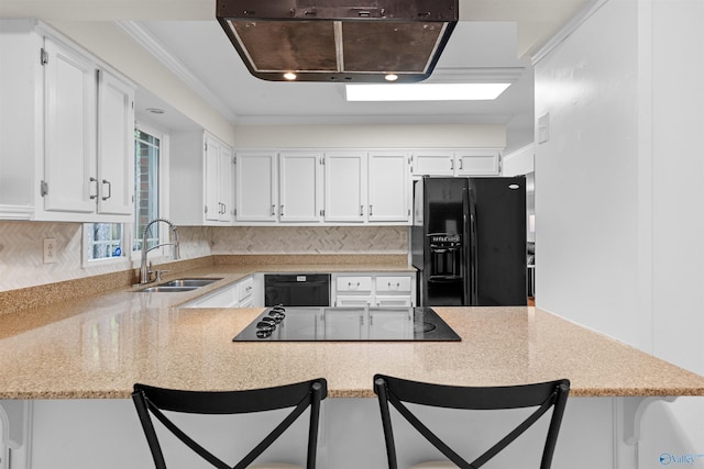 kitchen featuring a peninsula, a breakfast bar, a sink, white cabinets, and black appliances