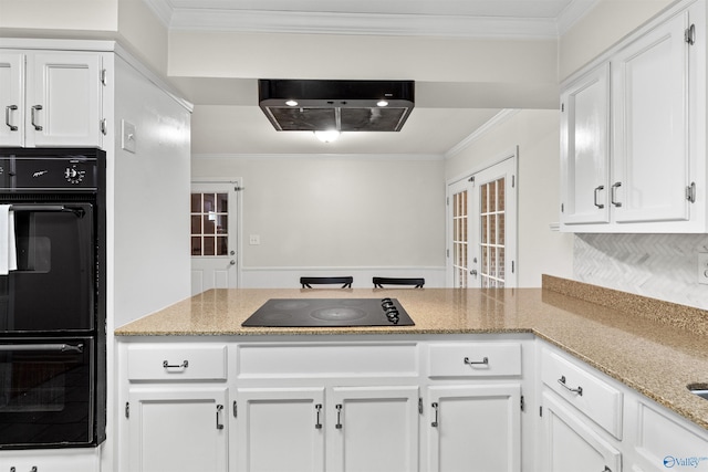 kitchen with light stone counters, a peninsula, white cabinetry, black appliances, and crown molding