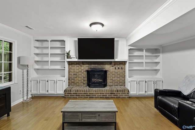 living room with a brick fireplace, light wood-type flooring, built in features, and crown molding