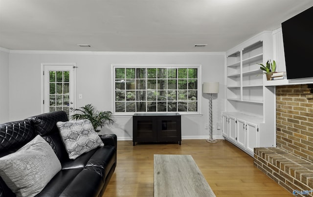 living area featuring visible vents, light wood-style flooring, and crown molding