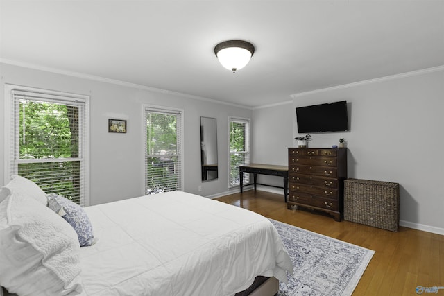 bedroom featuring crown molding, multiple windows, and wood finished floors