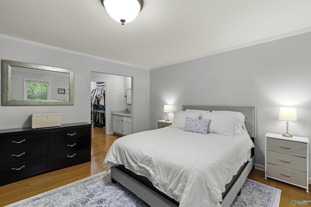 bedroom with a closet, wood finished floors, a walk in closet, and crown molding