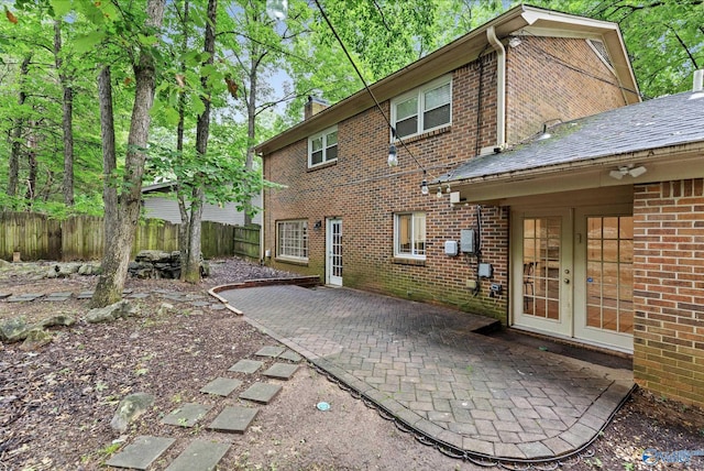 back of house with brick siding, a patio area, fence, and french doors