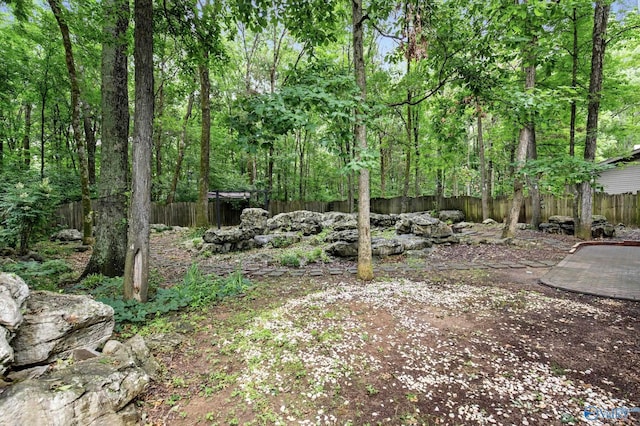 view of yard featuring a wooded view and fence