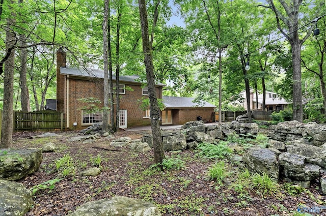 back of house featuring a patio area, brick siding, fence, and a chimney