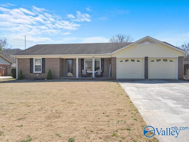 ranch-style home featuring a garage, driveway, brick siding, and a front yard