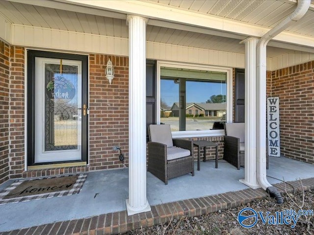 doorway to property featuring brick siding and covered porch