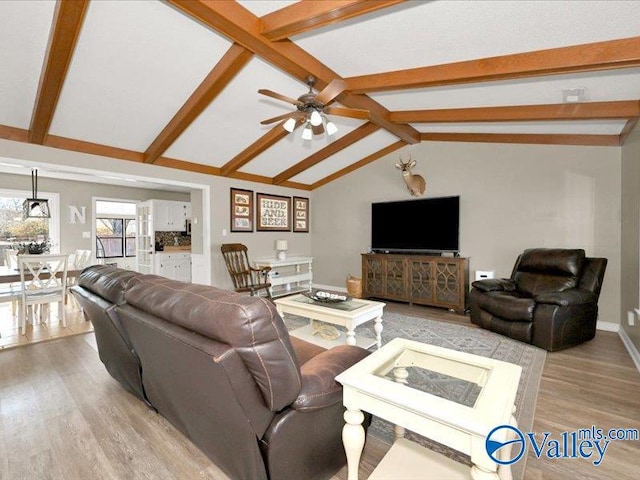 living room with lofted ceiling with beams, baseboards, light wood finished floors, and ceiling fan