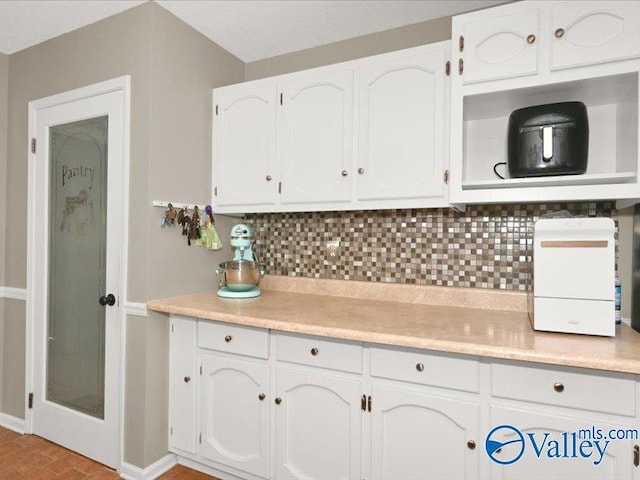 kitchen featuring tasteful backsplash, white cabinets, and light countertops