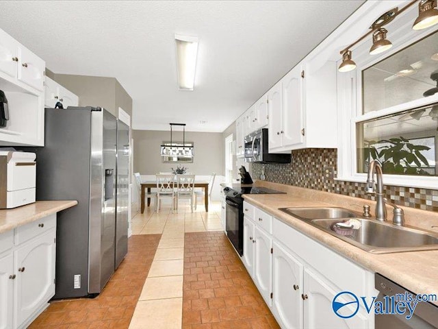 kitchen with light tile patterned floors, a sink, light countertops, appliances with stainless steel finishes, and white cabinetry